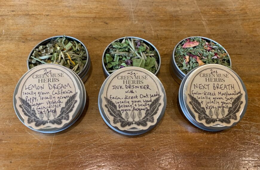 Four tins of herbal teas, perfect as seasonal stocking stuffers, on a wooden table.