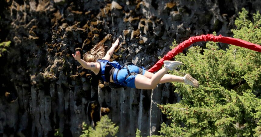 A woman benefiting from the thrilling experience of jumping off a cliff with a rope attached to her.