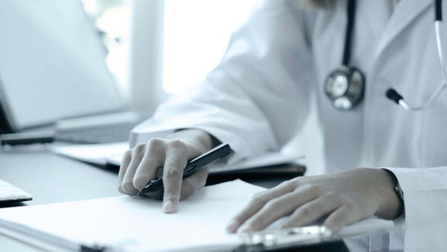 A female doctor from Canada writing a treatment plan for Lyme disease on a piece of paper.