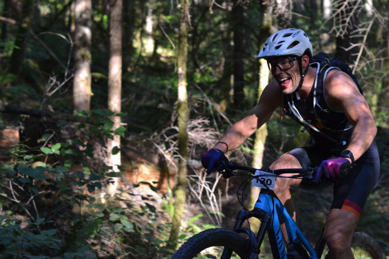 A man participating in the ITU World Cross Triathlon Championships rides his mountain bike through the woods at XTERRA Victoria.
