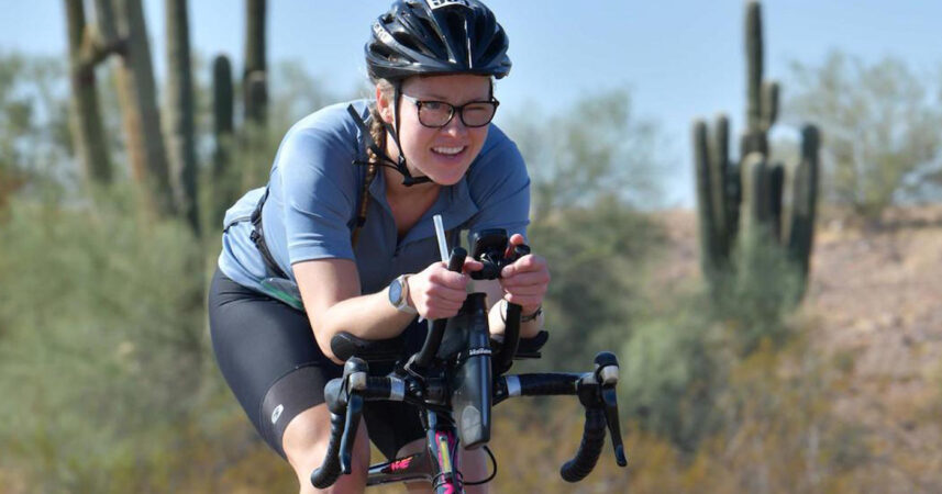 Madi Campbell riding a bike in front of a cactus at Ironman Arizona.