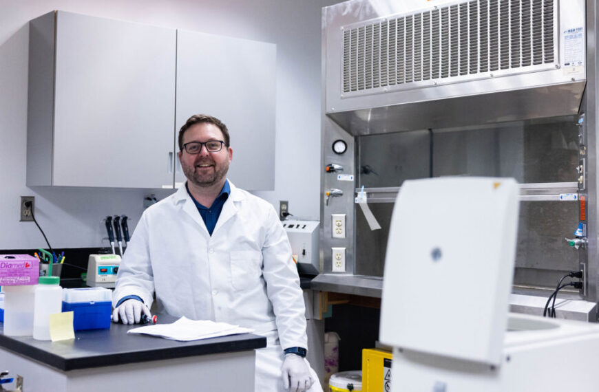 Dr. Adam Warner, a Conservation Genetics Scientist, standing in front of equipment at Raincoast lab.
