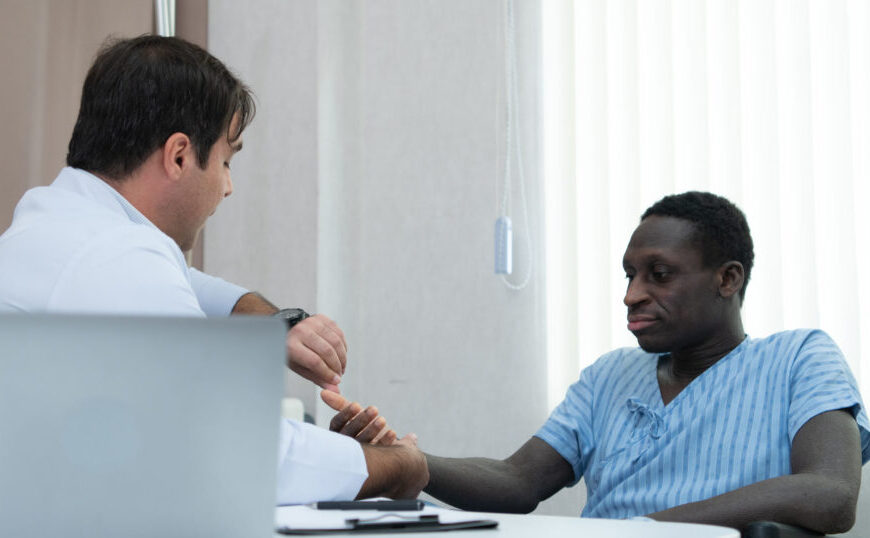 A Black man in a wheelchair is being examined by a doctor for diagnosis.