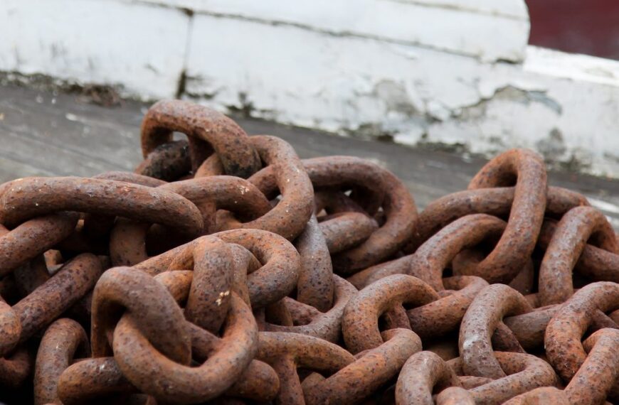On a wooden deck, a stack of rusty chains.