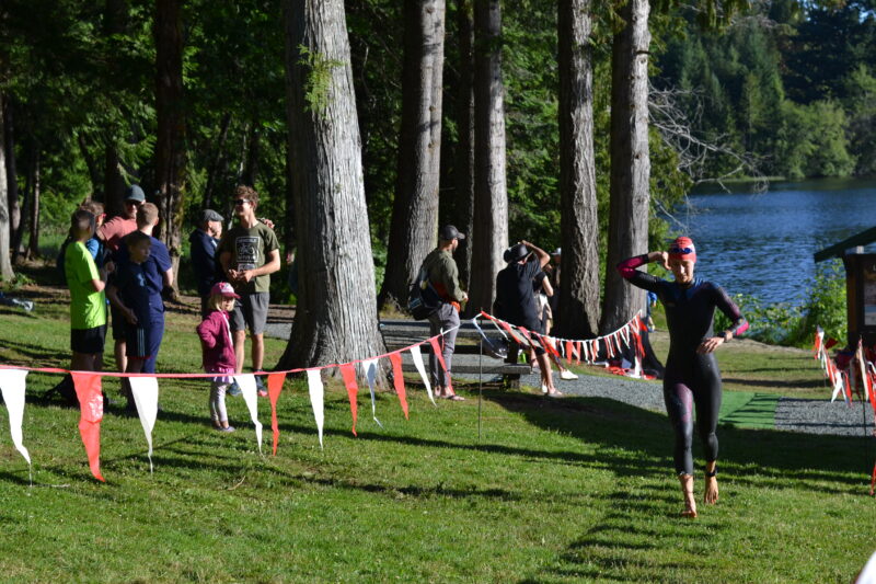 A group of people participating in the Cowichan Challenge race near a lake.