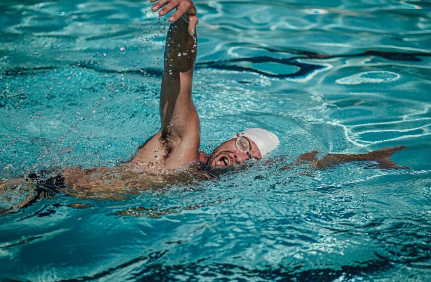 The man is unlocking his full performance as he swims in the pool, taking deep breaths underwater.