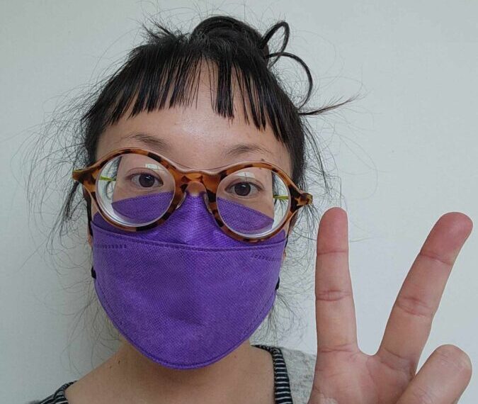 A woman wearing a purple face mask for masking purposes.