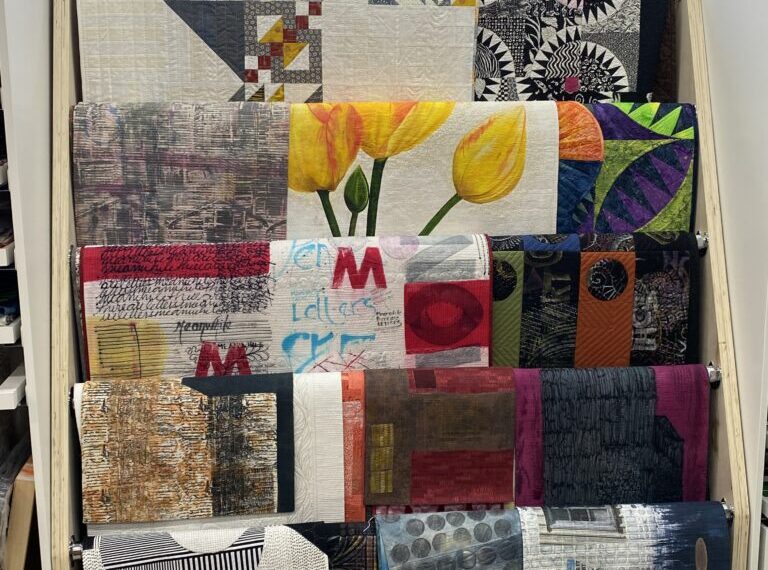 A room with a shelf displaying beautifully woven quilts, carefully wrapped and arranged for visual appeal.