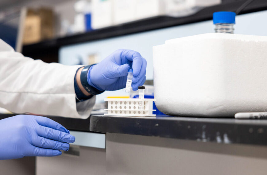 A man in a lab coat is placing a sample into a container, possibly involving DNA or underwater creatures.