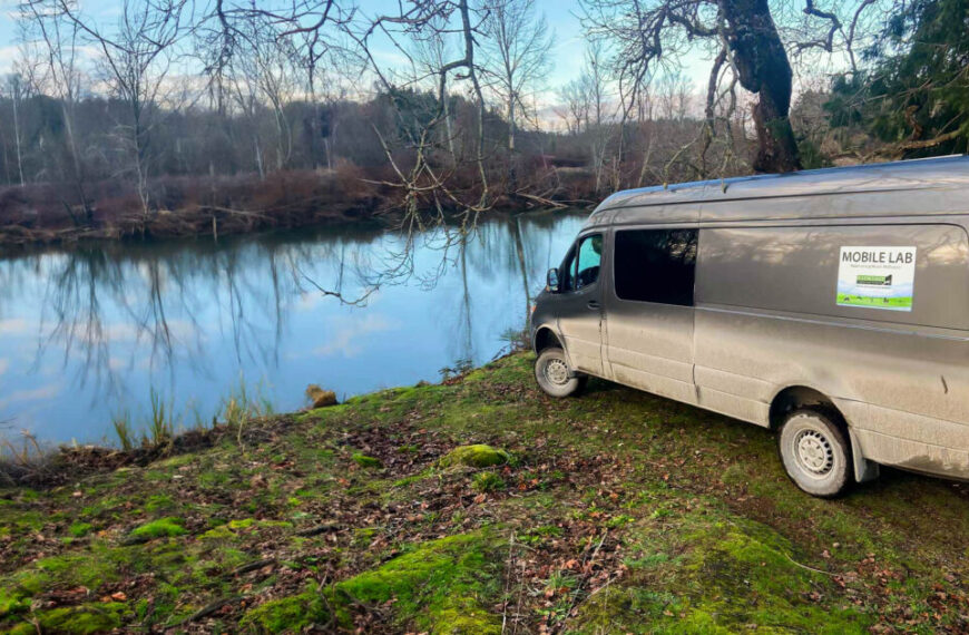 A silver van parked next to a river has futuristic plans to become a future mobile lab.