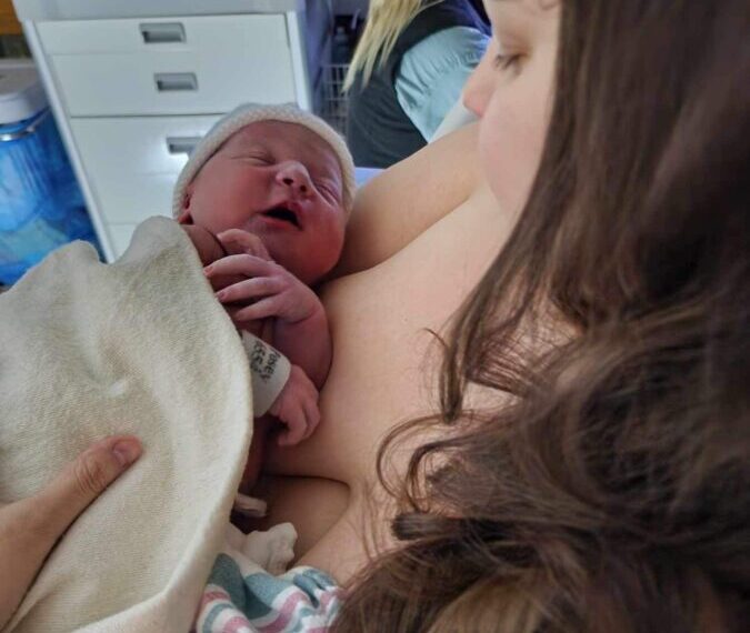 A newborn baby held by its mother with tender care shortly after birth.