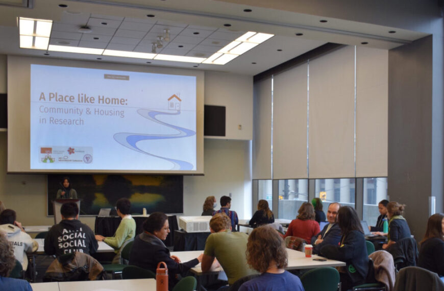 People attended a symposium titled "A Place Like Home: Community & Housing in Research" in a conference room, one year ago.