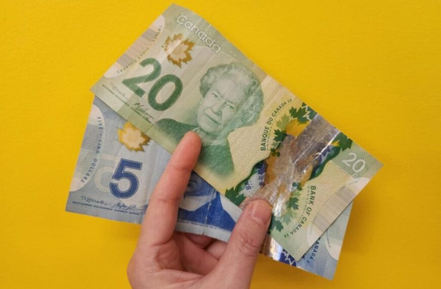 A hand holds Canadian currency, including a $5 and a $20 bill, against a bright yellow background—perfect for Cash Happy Hour on Mondays.
