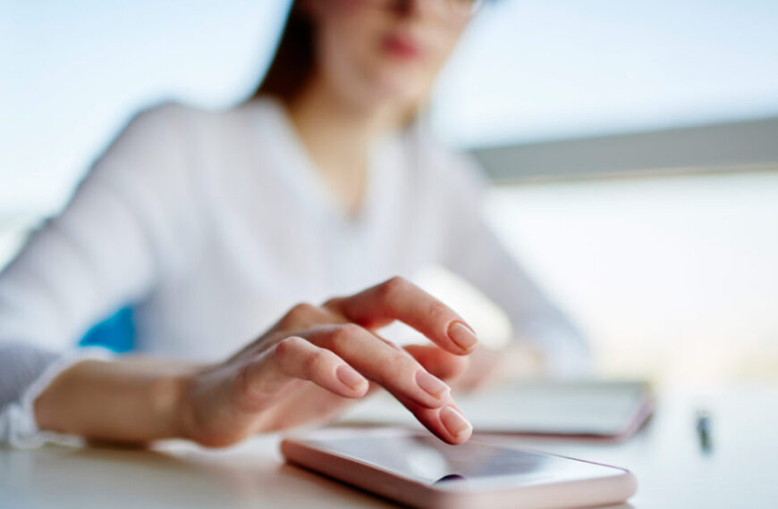 A person, engrossed in their smartphone on a table, seems to be participating in a patient survey for the Canadian Lyme Alliance. Nearby, a blurred notebook and pen hint at notes on Lyme disease research.