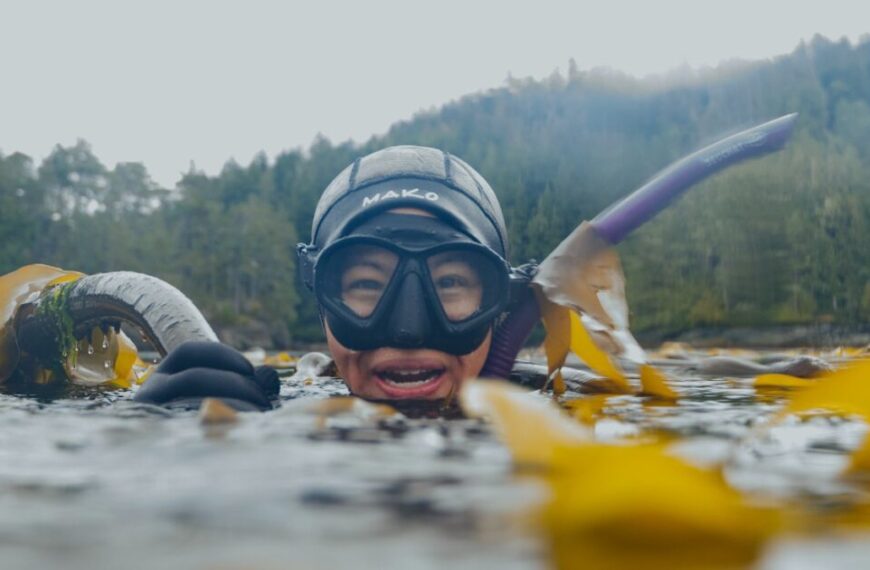 Amidst the swaying kelp, Maureen Vo glides effortlessly in her mask and snorkel. The serene waters whisper tales of her freediving adventures, while the lush forested shoreline stands as a backdrop to her burgeoning career route beneath the waves.