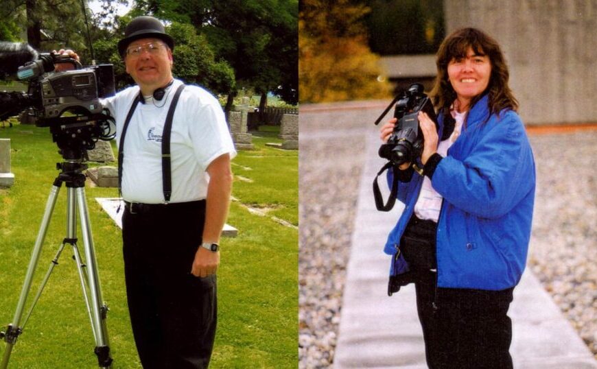Sue McDougall, in a white shirt and hat, films near gravestones while another person, possibly Gary McDougall in a blue jacket, stands on a gravel path. Could they be CanLyme volunteers documenting their work?.