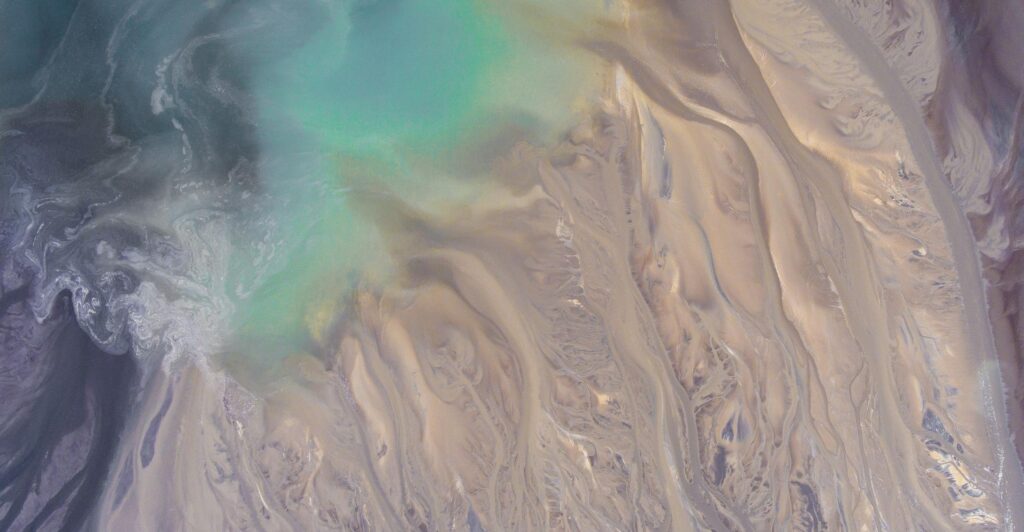 Stunning abstract aerial view showcasing turquoise waters blending with sandy textures, ideal for creative backgrounds.