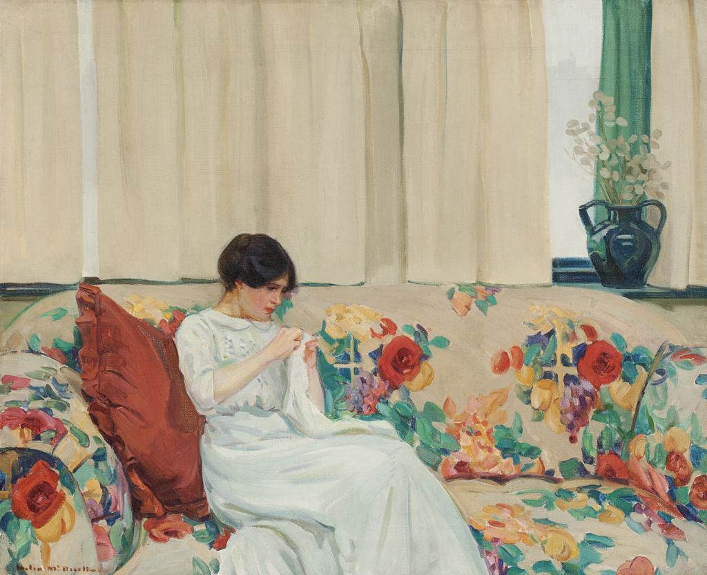 A feminine-coded person sits on a floral couch in a long white dress embroidering a white piece of cloth.
